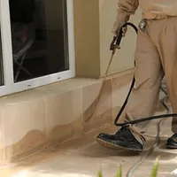 General pest control technician spraying exterior perimeter around a home in Phoenix, AZ